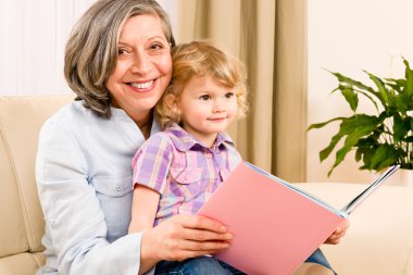 Grandmother and granddaughter read book together