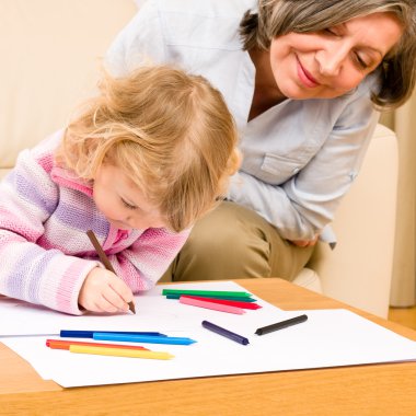 Grandmother and granddaughter drawing at home clipart