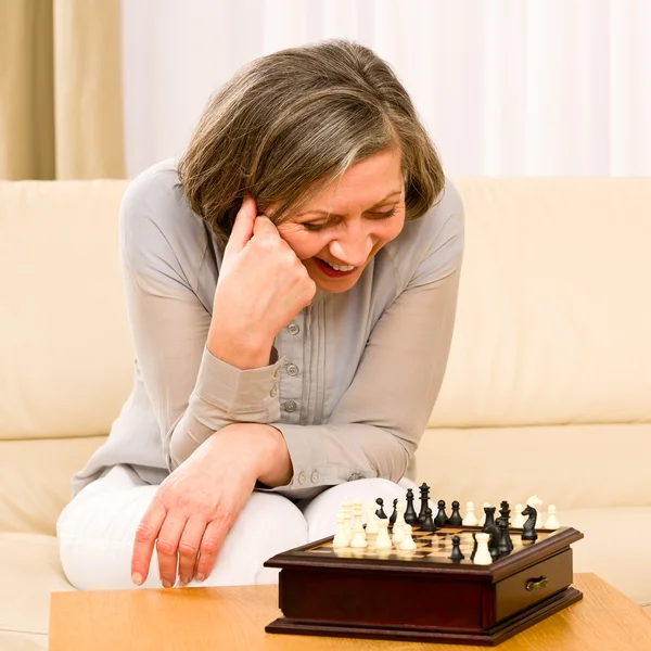 Starszy kobieta grać szachy szczęśliwy siedzieć na kanapie — Zdjęcie stockowe
