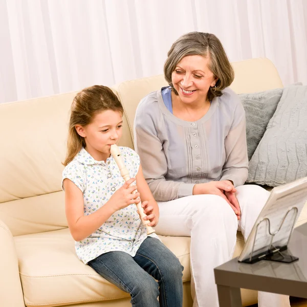 Бабушка учит молодую девушку играть на флейте счастливой — стоковое фото
