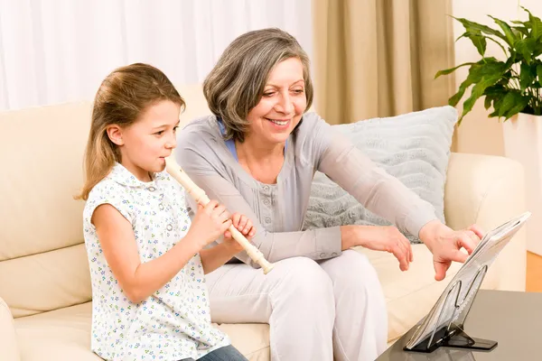 Бабушка учит молодую девушку играть на флейте счастливой — стоковое фото