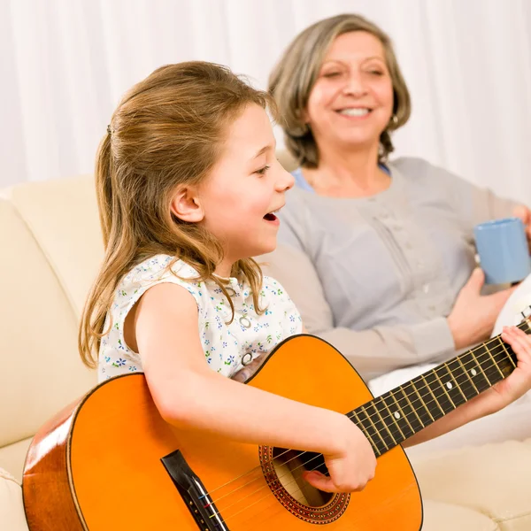Mladá dívka zpívat hrát na kytaru na babičku — Stock fotografie