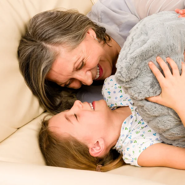 Бабушка с внучкой обнимаются на диване — стоковое фото