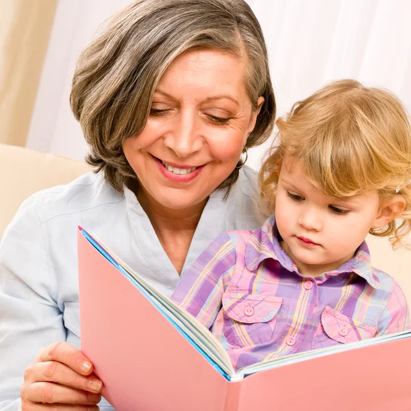 Grandmother and granddaughter read book together — Stok fotoğraf