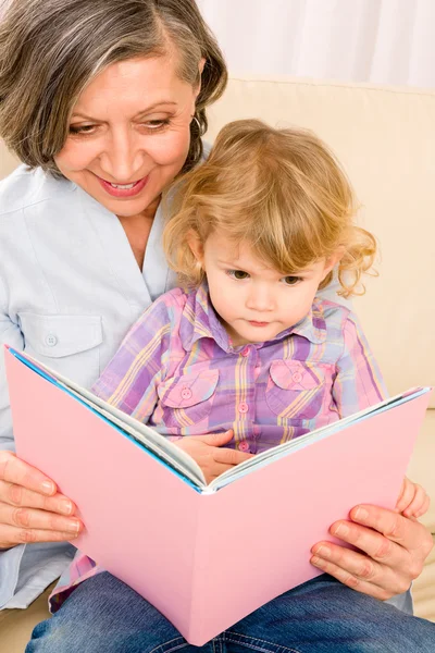 Grandmother and granddaughter read book together — Stok fotoğraf