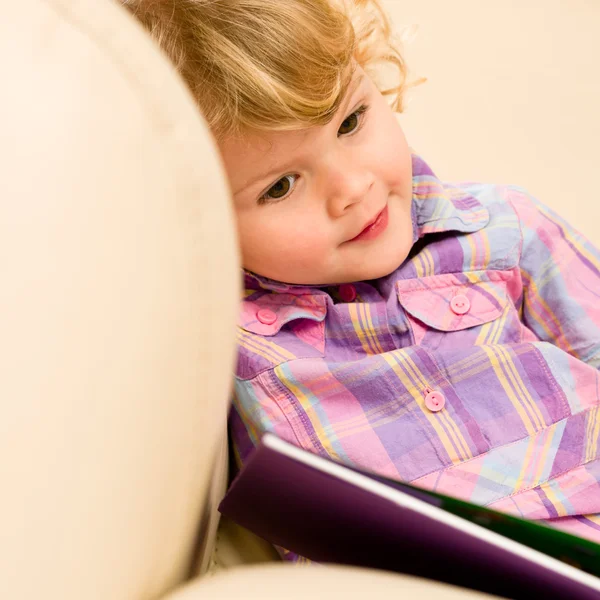 Bambina con libro guardando le foto — Foto Stock