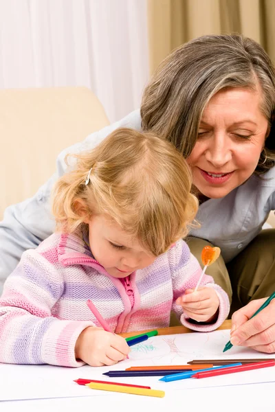 Nettes kleines Mädchen zeichnet mit Großmutter zu Hause — Stockfoto