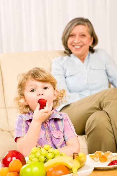 Menina come fruta de morango com avó — Fotografia de Stock
