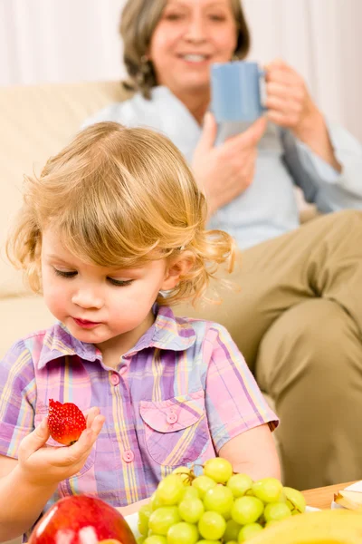 Menina come fruta de morango com avó — Fotografia de Stock