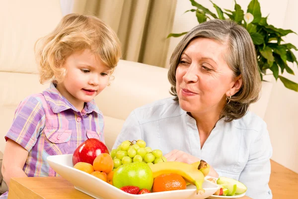 Abuela con nieta comer fruta en casa — Foto de Stock