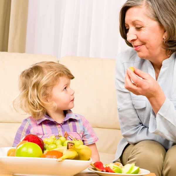 小さな女の子を見て祖母の果物を食べる — ストック写真