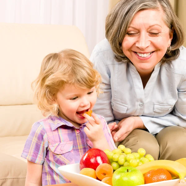 Kleines Mädchen isst mit Großmutter Aprikosenfrüchte — Stockfoto