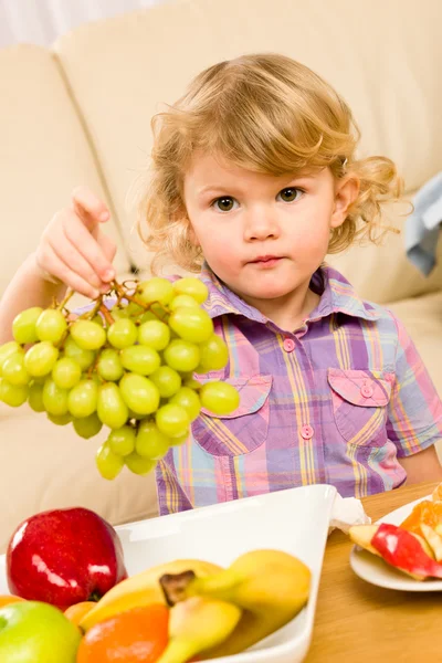 Schattig klein meisje houdt druiven fruitschaal — Stockfoto