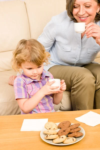 Маленькая девочка с бабушкой ест печенье — стоковое фото