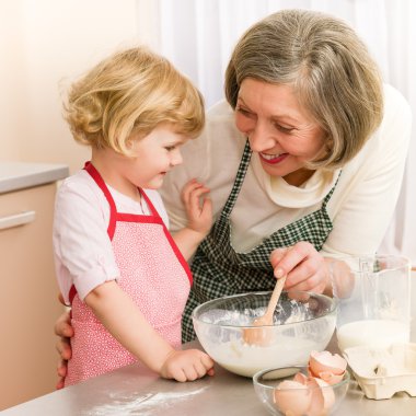 Child girl and grandmother baking cake clipart