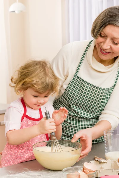 Grandmother and granddaughter whisk dough — Stock Photo, Image
