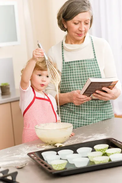 Funny little girl baking cupcake with grandma — Stock Photo, Image