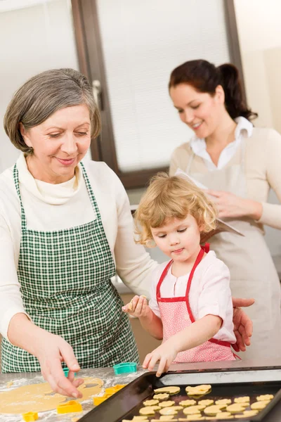 Маленькая девочка с бабушкой вырезает печенье — стоковое фото