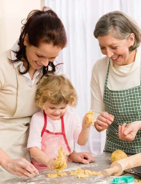 Маленькая девочка с матерью вырезает печенье — стоковое фото