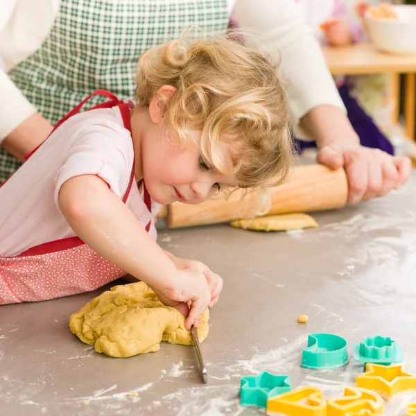 Pequena menina cortando massa para biscoitos — Fotografia de Stock