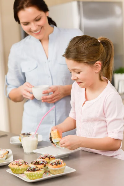女の子に少し味を振りかけるママとカップケーキ — ストック写真