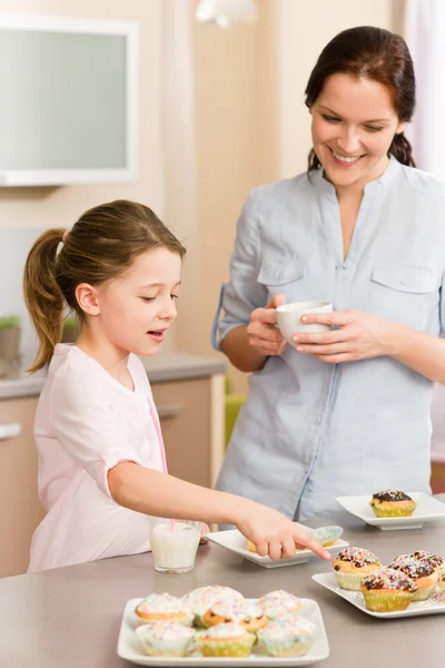 Маленькая девочка указывает кексом на свою мать — стоковое фото