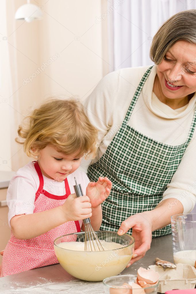 Grandmother and granddaughter whisk dough