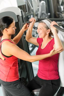 Personal trainer assist senior woman at gym clipart