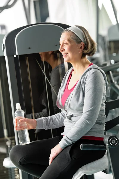 Senior woman relax sitting by fitness machine — Stock Photo, Image