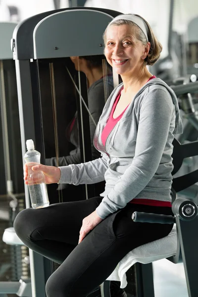 Kadın kıdemli relax fitness makine tarafından oturan — Stok fotoğraf
