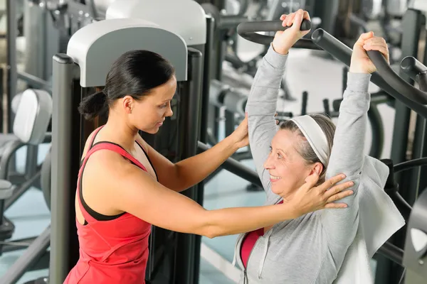 Exercício da mulher sênior na máquina da imprensa do ombro — Fotografia de Stock