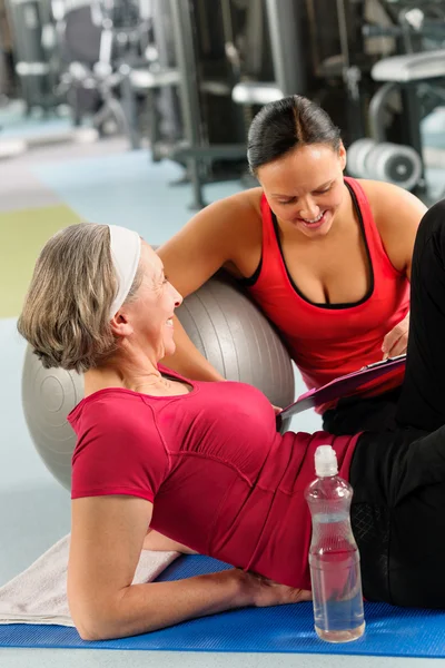 Senior woman on mat with personal trainer — Stock Photo, Image