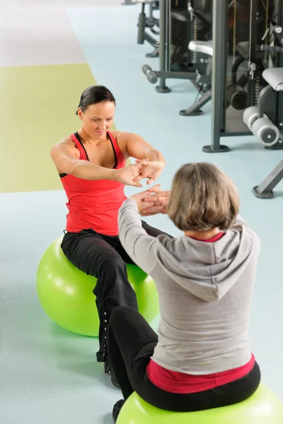 Senior vrouw met trainer uitrekken fitness bal — Stockfoto