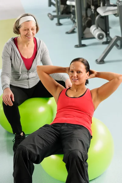 Senior vrouw met trainer uitoefening fitness bal — Stockfoto