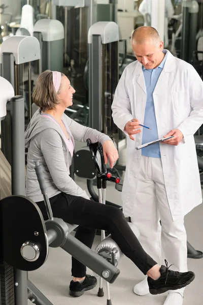 Физиотерапевт помогает активной пожилой женщине в спортзале — стоковое фото