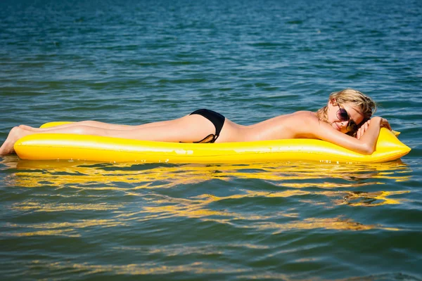 Sommerfrau schwimmt auf gelber Wassermatratze — Stockfoto