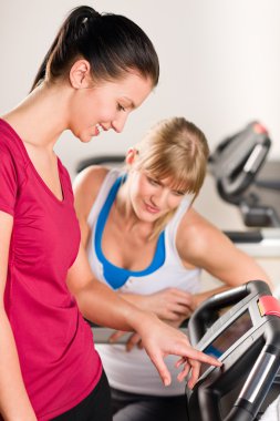 Young women on treadmill giving instructions clipart