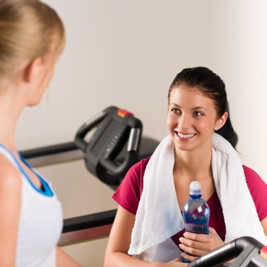 Young female friends chatting in fitness center clipart