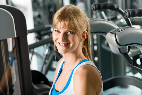Lachende vrouw op fitness center-oefening machine — Stockfoto