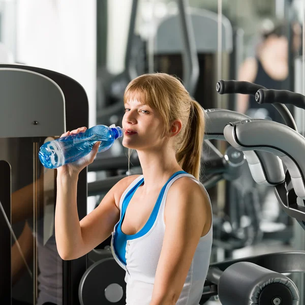 Vrouw drinkwater bij fitnesstoestel — Stockfoto