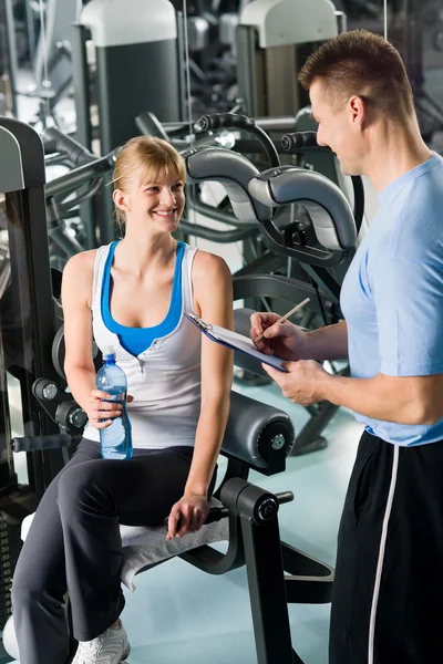 Completando plano de fitness pessoal com treinador — Fotografia de Stock