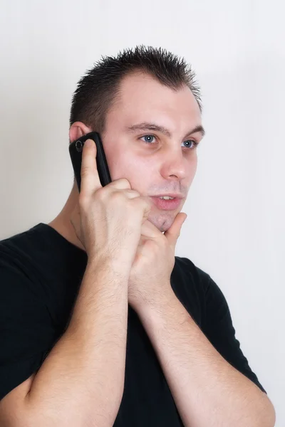 Ung man pratar med någon med hans mobiltelefon — Stockfoto