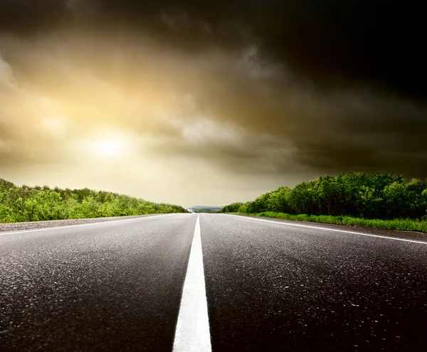 Céu tempestuoso e estrada na floresta — Fotografia de Stock