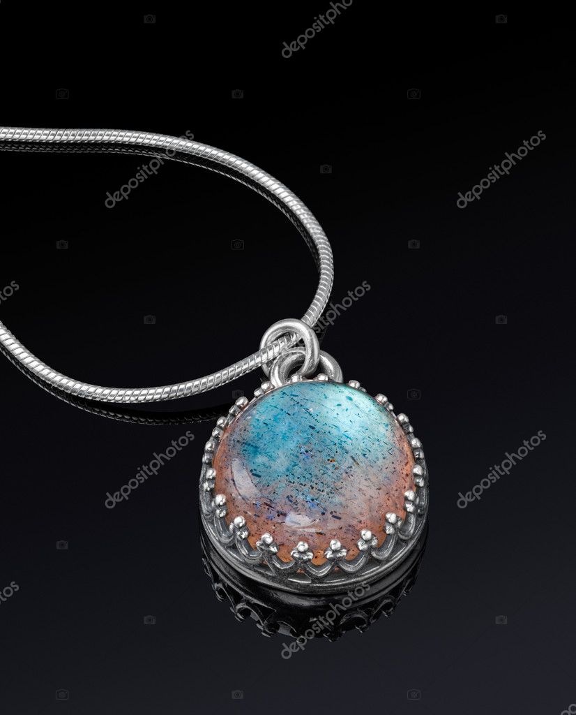 Round silver jewelry pendant on black background. Stock Photo by