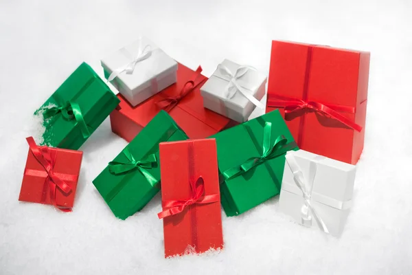 Kleur geschenkdozen geïsoleerd op een witte achtergrond in de sneeuw. — Stockfoto