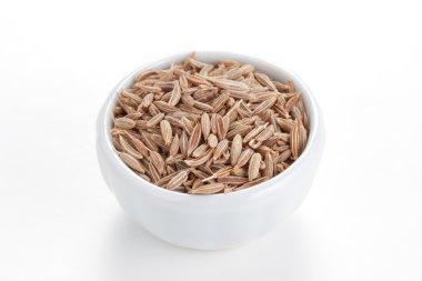 Cumin seeds in a white bowl on white background. clipart