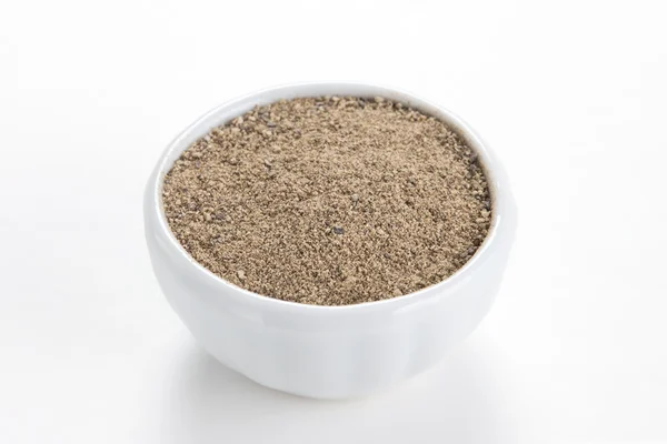 Black pepper ground (Piper nigrum) in a white bowl on white back — Stock Photo, Image