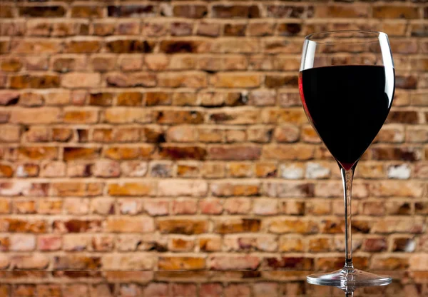 Copo de vinho no fundo de uma parede de tijolo — Fotografia de Stock