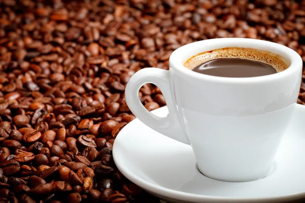 ถั่วกาแฟกับถ้วยสีขาว — ภาพถ่ายสต็อก