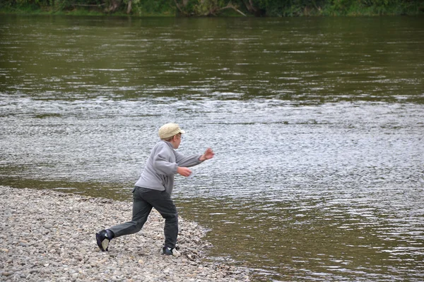 Garçon jetant de la pierre dans la rivière — Photo